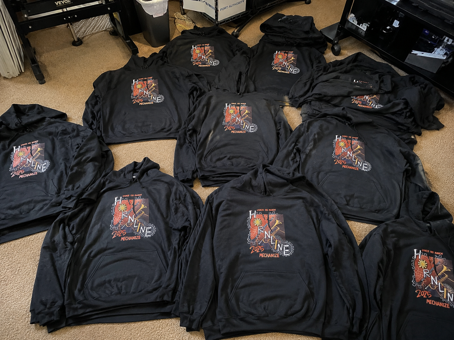 Black marching band hoodies laid out after printing.